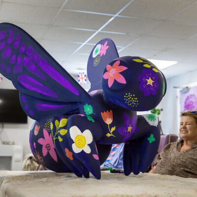 A large sculpture of purple bee with flowers drawn on it
