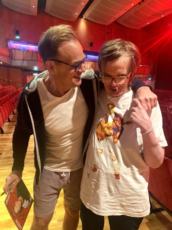 Jason and his fan hugging and looking at the camera