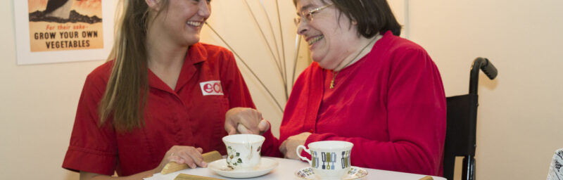 Smiling carer helping out older women