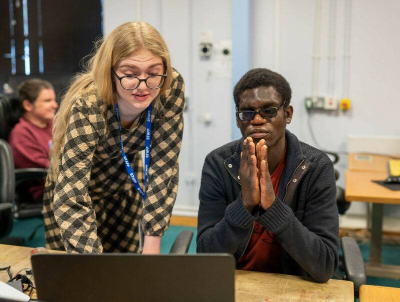 Carer helping man on laptop