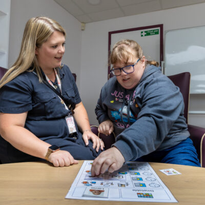 A support worker helping a lady with a learning disability and autism to make choices using a picture timetable.