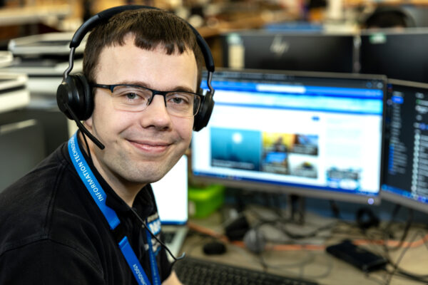 A young man wearing a headset and looking at the camera