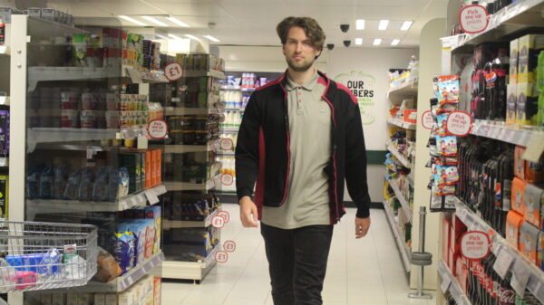 Zach in Co-op uniform walking past different shelves with products.