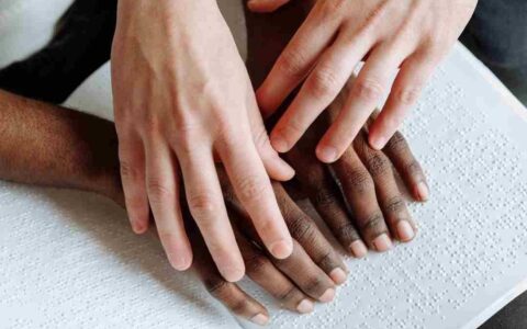 A person helping another person read braille