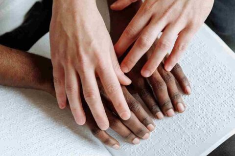 A person helping another person read braille