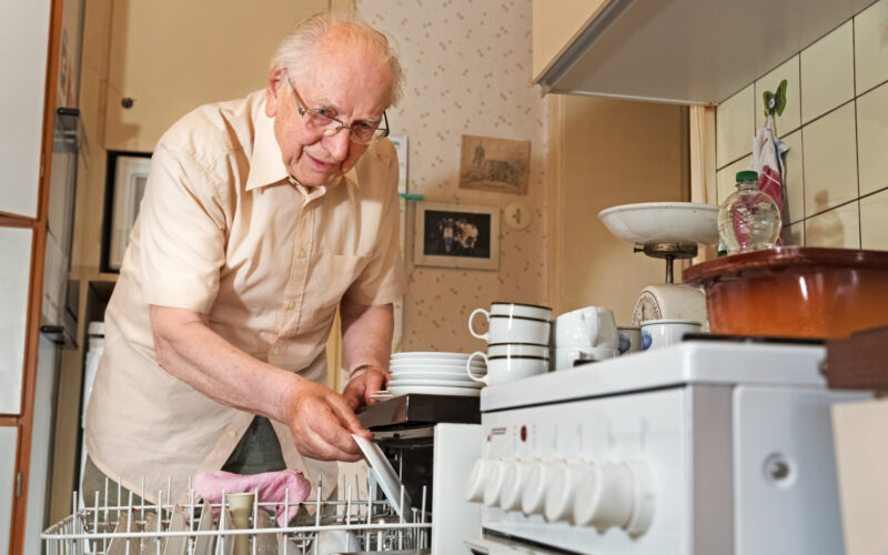 An elderly man cleaning the dishes