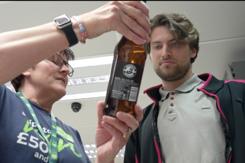 Young man with autism working at East of England Co-op, getting instructions from supervisor.