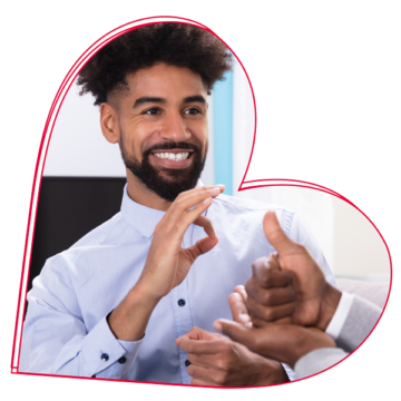 Man smiling and helping out someone with slight and hearing impairments