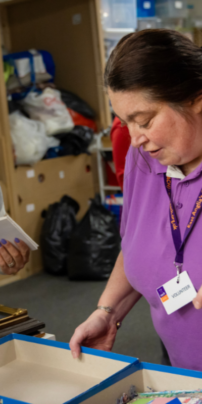 Elaine and another person sorting through item donations at the charity shop