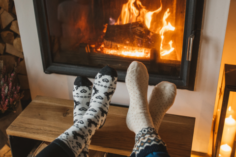 2 people enjoying the warmth of an indoor fireplace