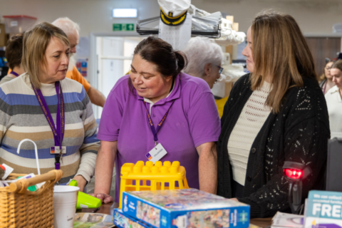 Elaine sorting through items at EACH charity shop with two other people